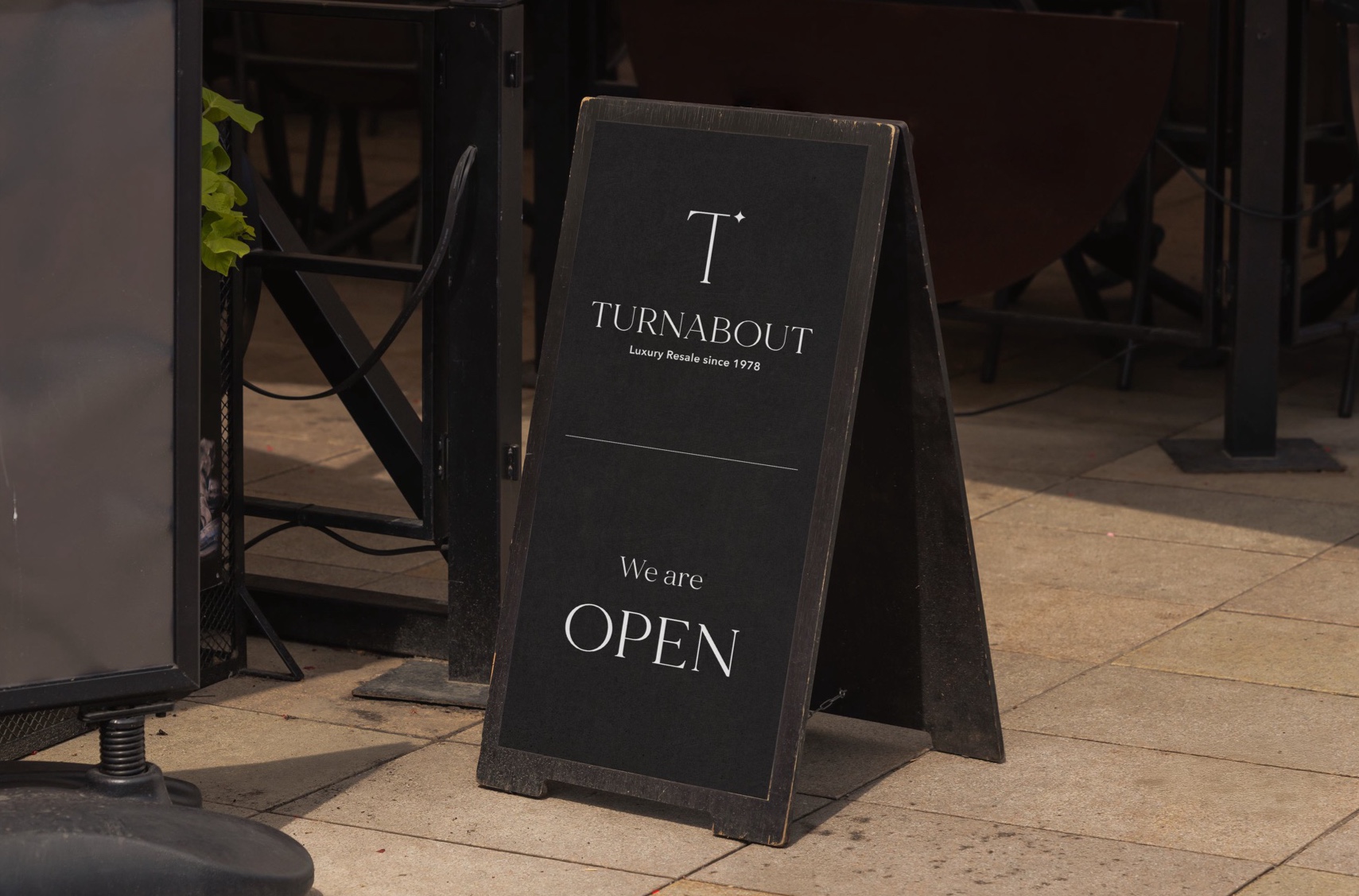 A black sidewalk A-frame sign reading ‘We are OPEN’ beneath the Turnabout logo.